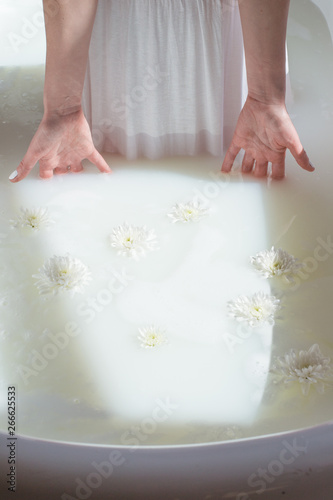photo women's dress and hands dropped in a natural milk bath with foam and flowers © alien_zagrebelna