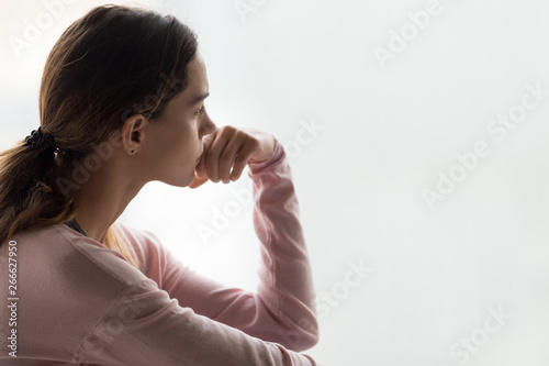 Pensive woman sitting indoors lost on thoughts side view face photo