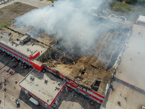 Burning industrial building. Smoke, collapsed roof aerial view