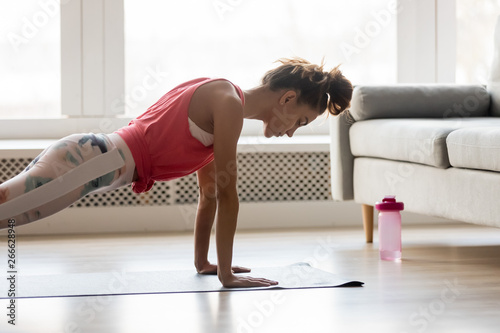 Sportive girl doing push press ups exercise at home