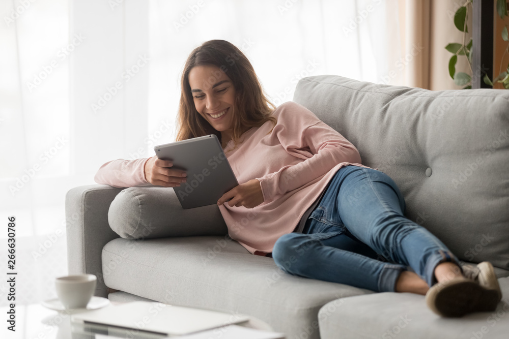 Woman lying on couch with tablet spending time at home Woman lying on couch with tablet spending time at home