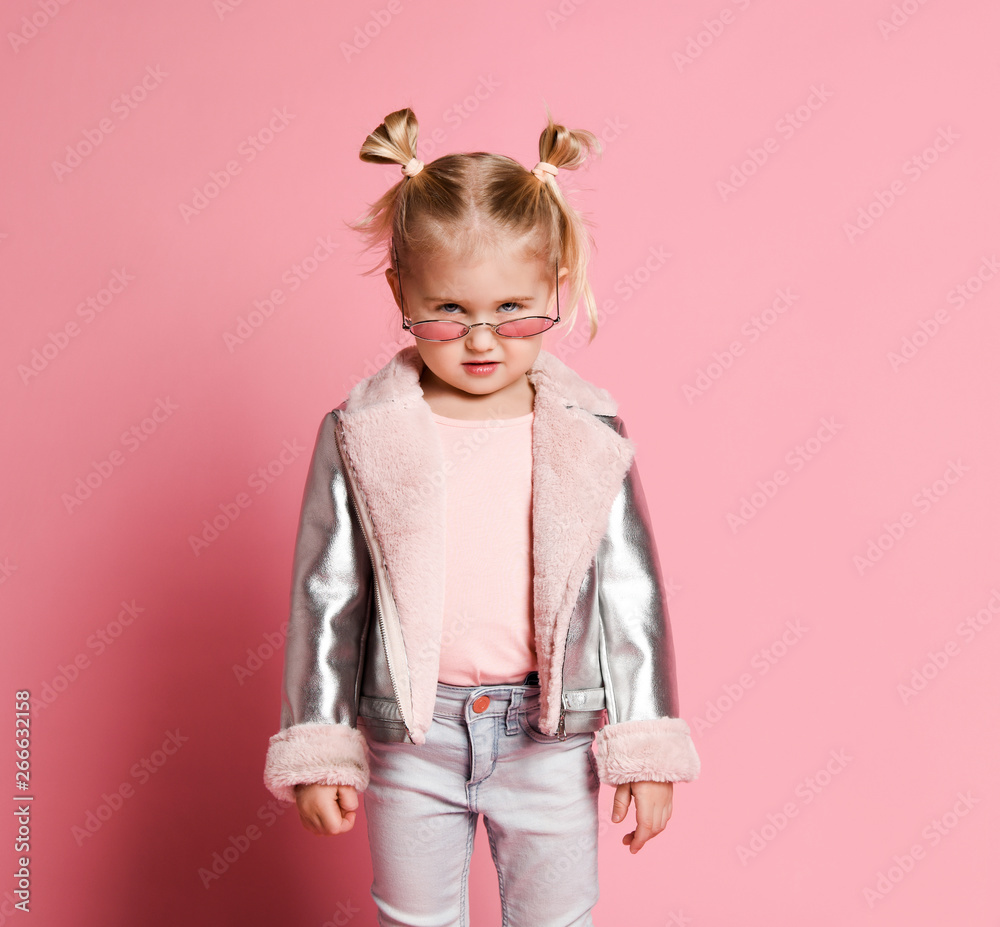 Portrait of a little girl in stylish clothing posing on pink background and playing up Portrait of a little girl in stylish clothing posing on pink background and playing up