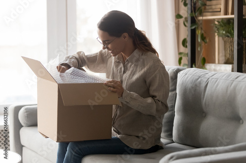 Quadro em tela Woman holds big carton box on laps unpack delivered goods