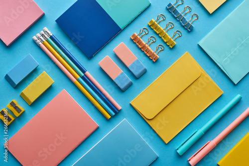 top view of notebooks and arranged colorful stationery isolated on blue photo