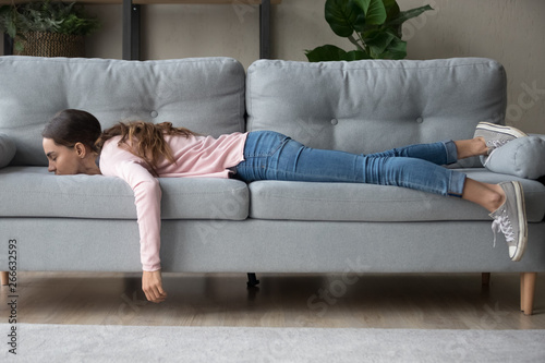 Young woman lying buried her face in sofa feels tired photo