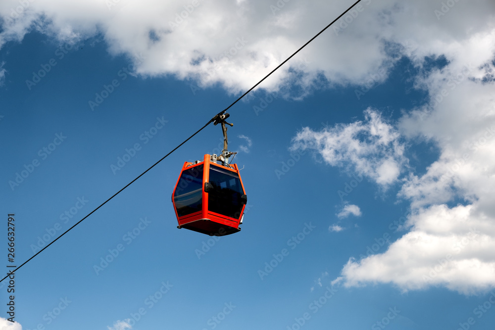 Single red cable car on cableway isolated on blue sky Single red cable car on cableway isolated on blue sky