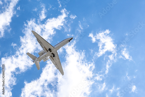 Low flying airplane; blue sky with white clouds background
