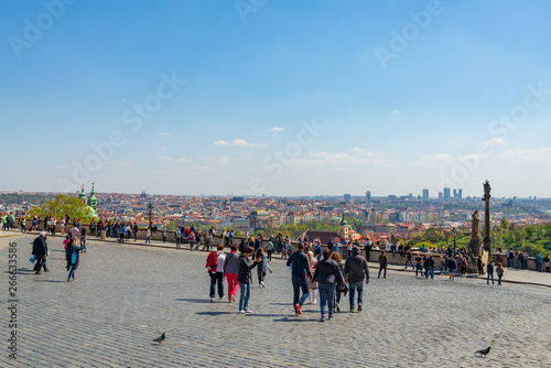 Tourists enjoy outdoor sunny day at Hradcany square near Prague Castle and background of aerial top panoramic view of Prague historical old town city skyline in Prague, Czech Republic..