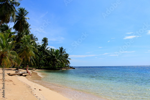 Young beautiful woman enjoying her time and resting close to the sea in the southern beach of "Pelicano" Island, close to Yandup Island lodge, kuna indians territory, San Blas, Panama.