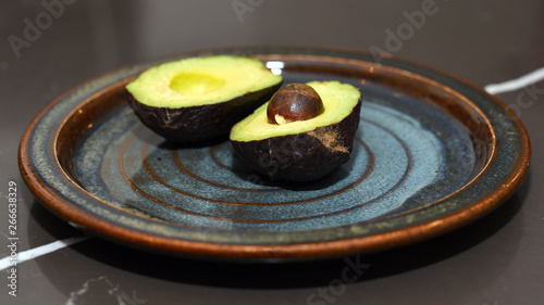 Avocado cut in half on ceramic plate