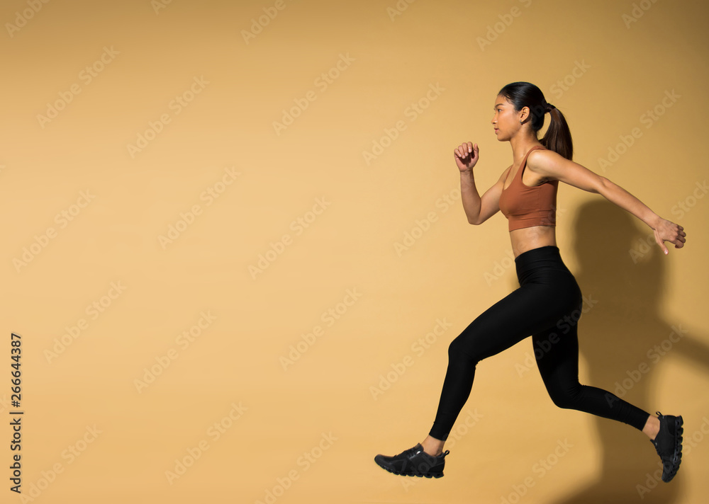 Asian slim Fitness woman exercise warm up stretch arms legs, studio lighting yellow beige mustard background shadow copy space, concept Woman Can Do athlete Sport 6 packs
