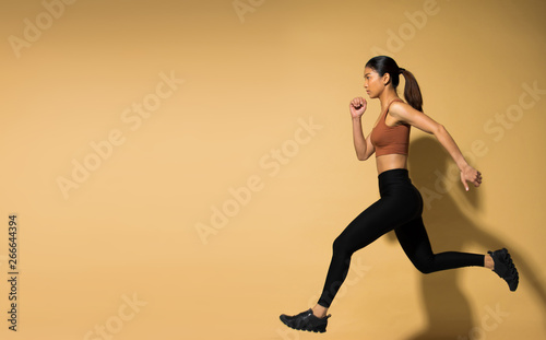 Asian slim Fitness woman exercise warm up stretch arms legs, studio lighting yellow beige mustard background shadow copy space, concept Woman Can Do athlete Sport 6 packs