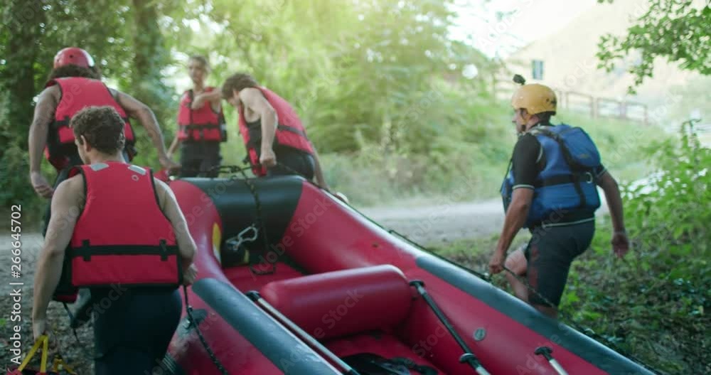 Group of people bringing raft boat after rafting on river during sunset ...