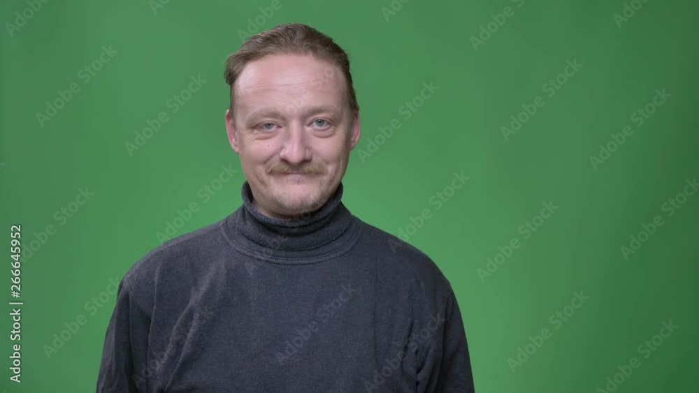 Portrait of blonde middle-aged man with beard watching gladly into camera on green background. Portrait of blonde middle-aged man with beard watching gladly into camera on green background.