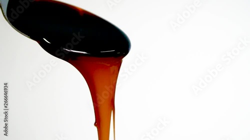 Molasses pours from spoon, slow motion, close up photo