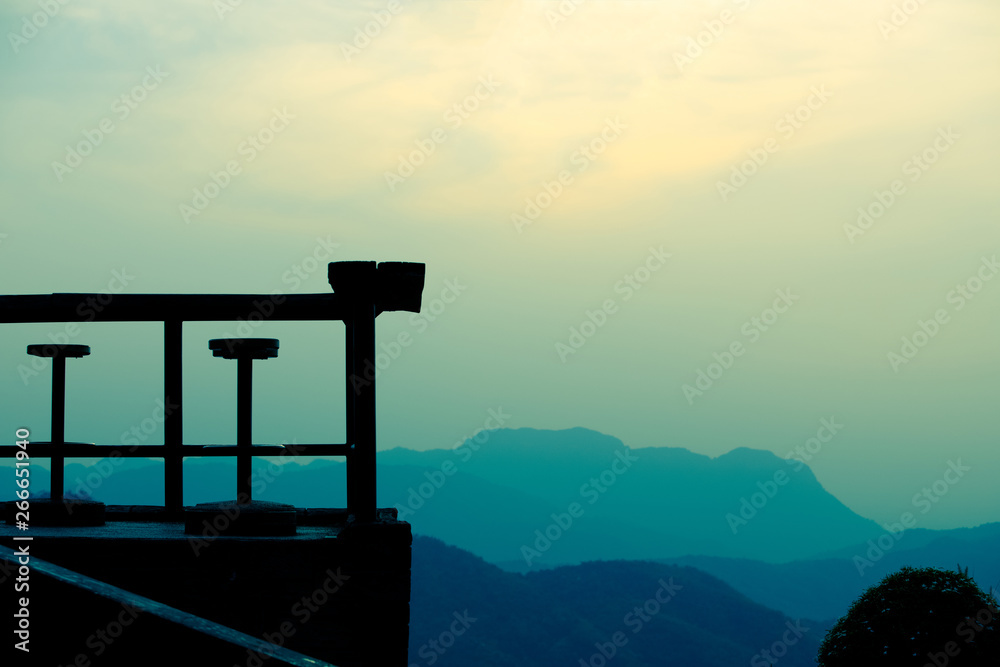 Silhouette of a wooden chair on a coffee shop with beautiful mountain background in the morning,wooden chair and  mountain 