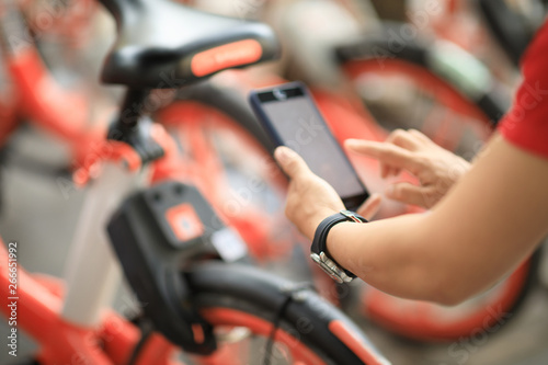 Hands using smartphone scanning the QR code of shared bike in city