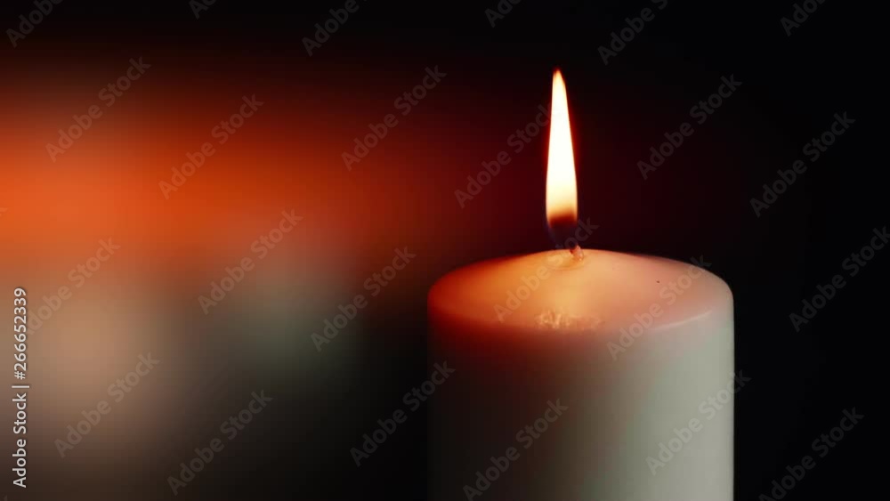 The showcases of colorful single candlelight on black background with the effect of light and slow motion. The showcases of colorful single candlelight on black background with the effect of light and slow motion.