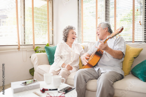 Meaningful moments. Lover senior couple sing a song together. Husband playing a guitar and wife is singing.