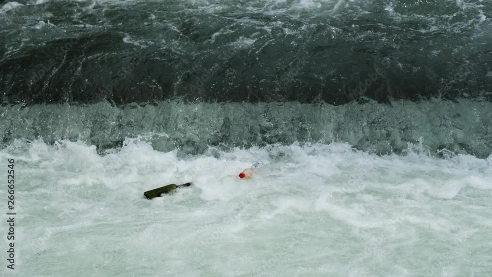 Environmental pollution. Footage of plastic and glas bottles swimming in water swirl behind a water fall. Pollution floating in water