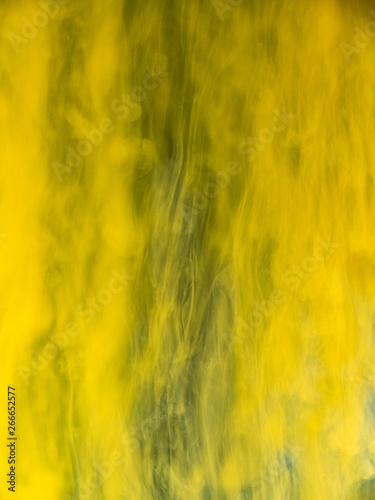 Yellow paint dissolving into water, abstract background. Close up view. Blurred background. Acrylic flows mixing with liquid, abstract pattern. Abstract yellow flows under water