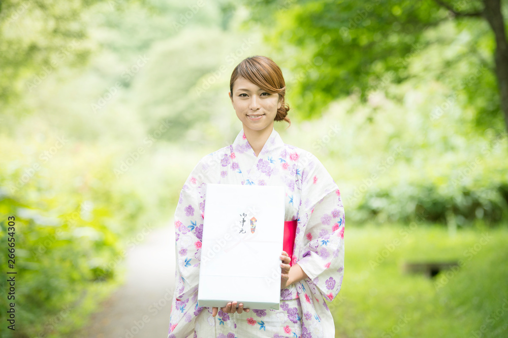 お中元を持ち微笑む浴衣姿の女性 お中元を持ち微笑む浴衣姿の女性