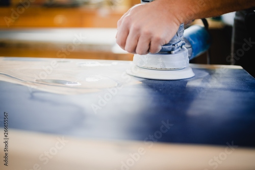 Woodworker using orbtail sander with epoxy table