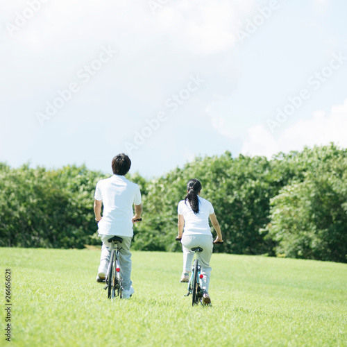 草原で自転車に乗るカップルの後姿