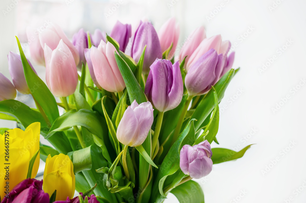 A beautiful bouquet of colorful spring tulips stands on the window. Close-up A beautiful bouquet of colorful spring tulips stands on the window. Close-up