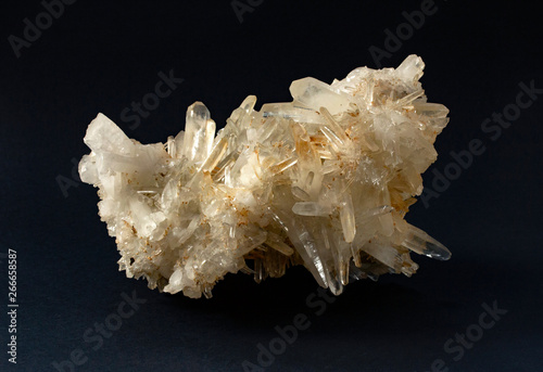 Scolecite mineral sample. White yellowish cluster of crystals in black background. Scolecite is a tectosilicate mineral belonging to the zeolite group.