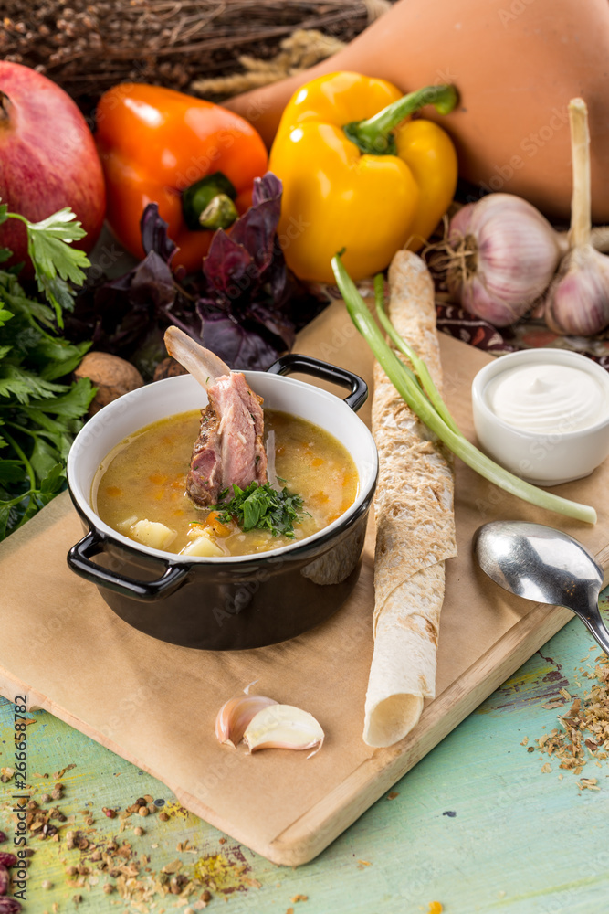 Shurpa soup with lamb in pot on blue wooden table