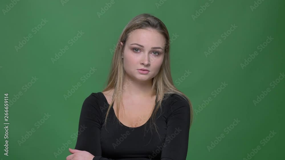 Portrait of young businesswoman in black blouse watching sadly into camera at green background. Portrait of young businesswoman in black blouse watching sadly into camera at green background.