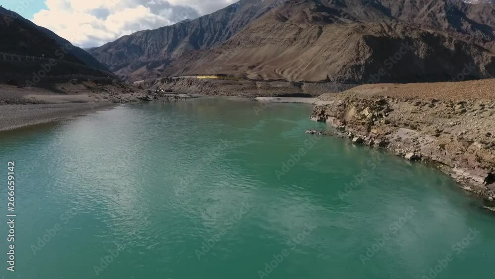 Drone, exterior, pushing in, medium wide shot of camera flying over blue river running towards mountain. Drone, exterior, pushing in, medium wide shot of camera flying over blue river running towards mountain.