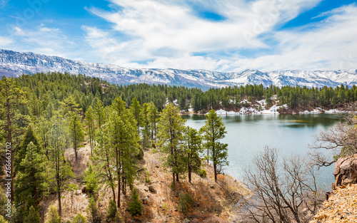 A fresh water lake is surrounded by a forest of Pine trees and towering snow capped mountains in this wilderness area outside of Durango, Colorado. Natural beauty everywhere you look is good for you