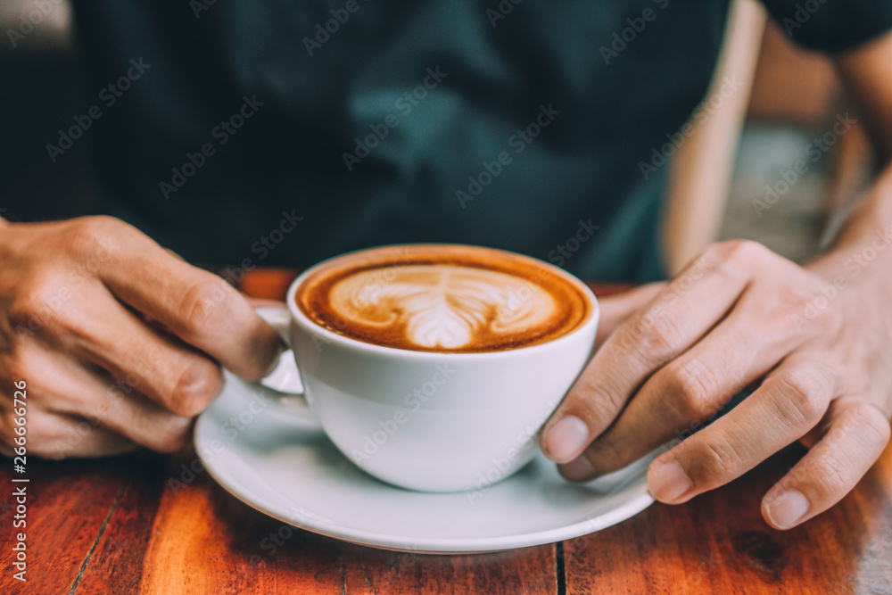 Hand holding a cup of coffee latte And Drinking Coffee