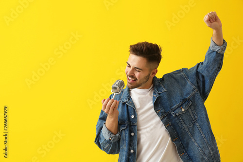 Handsome male singer with microphone on color background photo