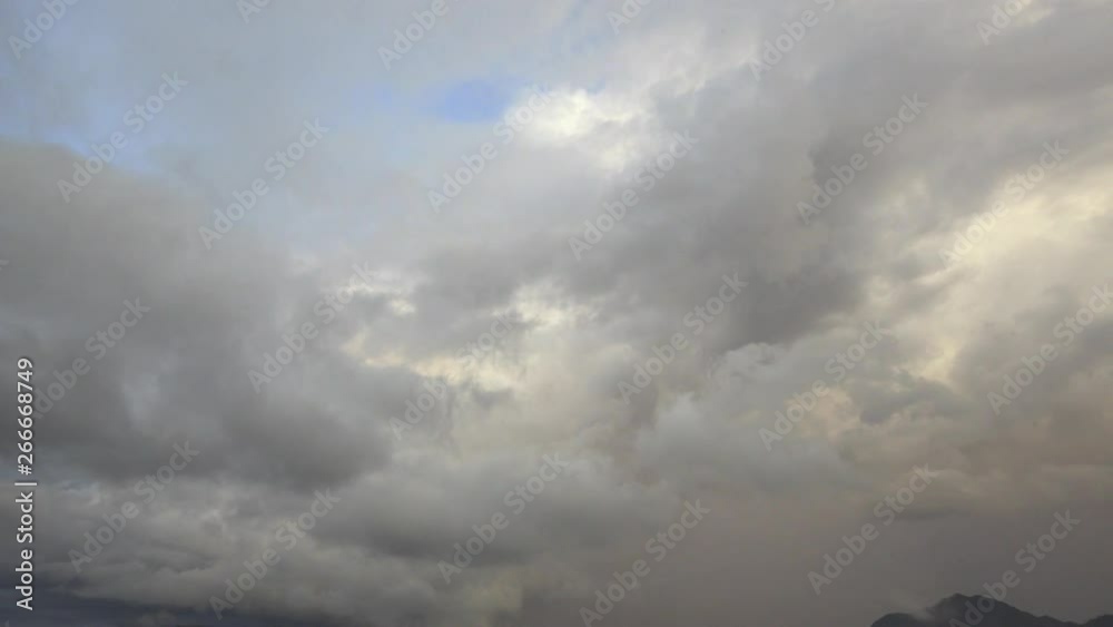 Tilt down from dramatic cloudscape to overcast, tropical lush landscape of Laos skyline. Misty mountain ranges above beautiful idyllic plantation farmland & agricultural village housing. Tilt down from dramatic cloudscape to overcast, tropical lush landscape of Laos skyline. Misty mountain ranges above beautiful idyllic plantation farmland & agricultural village housing.
