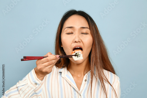 Asian woman eating sushi on...