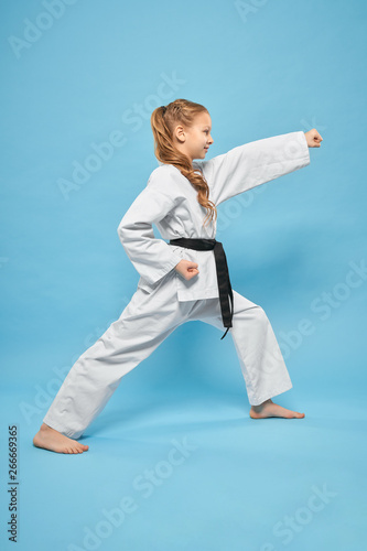 Side view of strong girl in kimono standing in karate stance