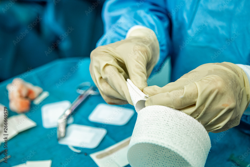 Φωτογραφία A nurse with latex gloves cuts strips of bandage in preparation to care for an injured person