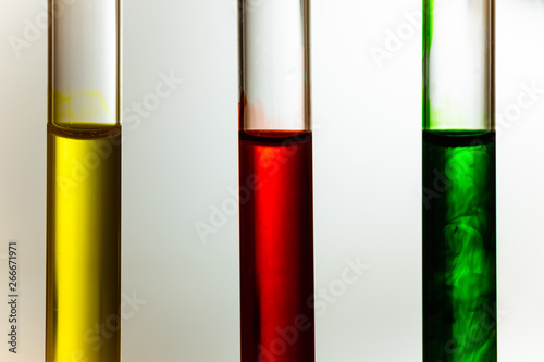 red green yellow solution dilute in clear liquid in test tube, close up photo