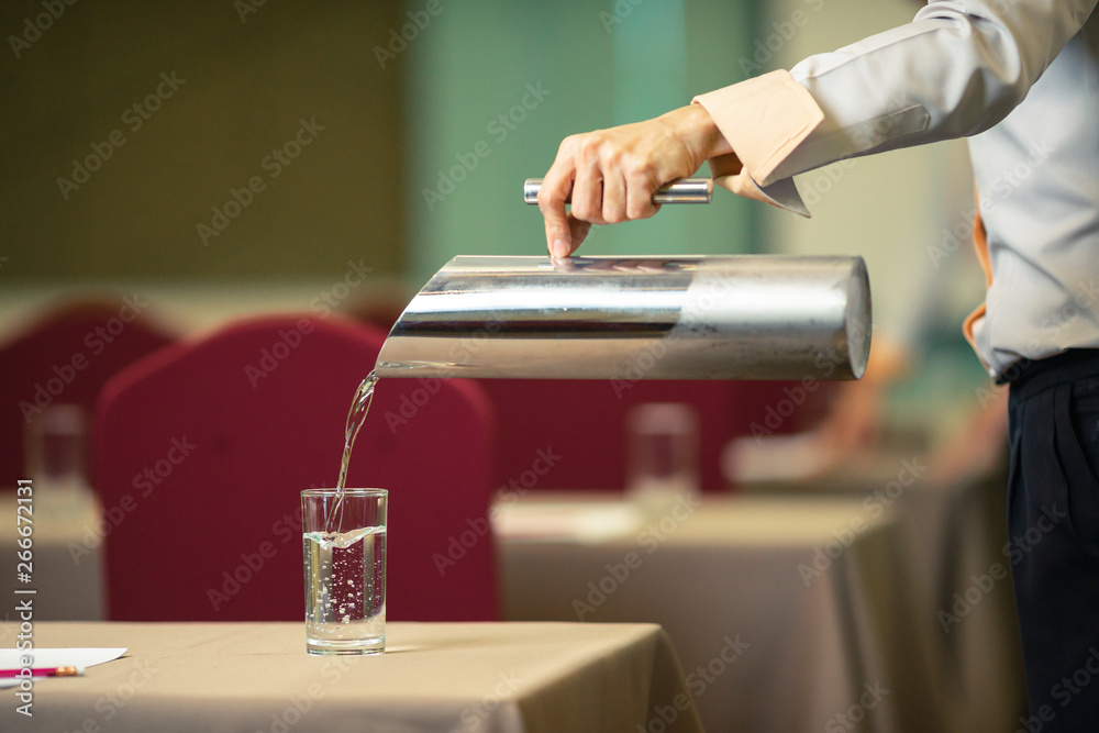 Hotel staff who are Pour drinking water into the glass in the seminar room.