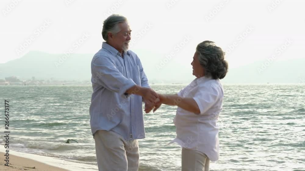 Asian couple senior dancing and relax summer on the beach together. Concept of happy family, post retirement, quality life, mental health and positive psychology. Asian couple senior dancing and relax summer on the beach together. Concept of happy family, post retirement, quality life, mental health and positive psychology.
