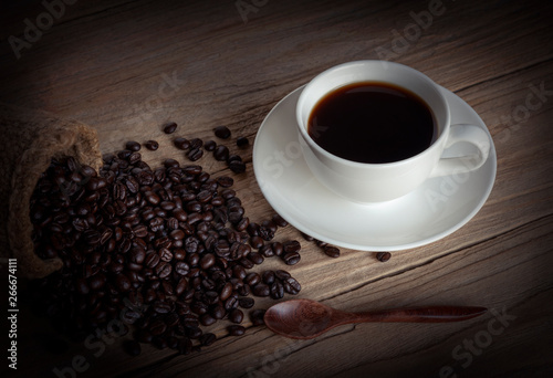 cup of coffee and coffee beans in a sack on wood background