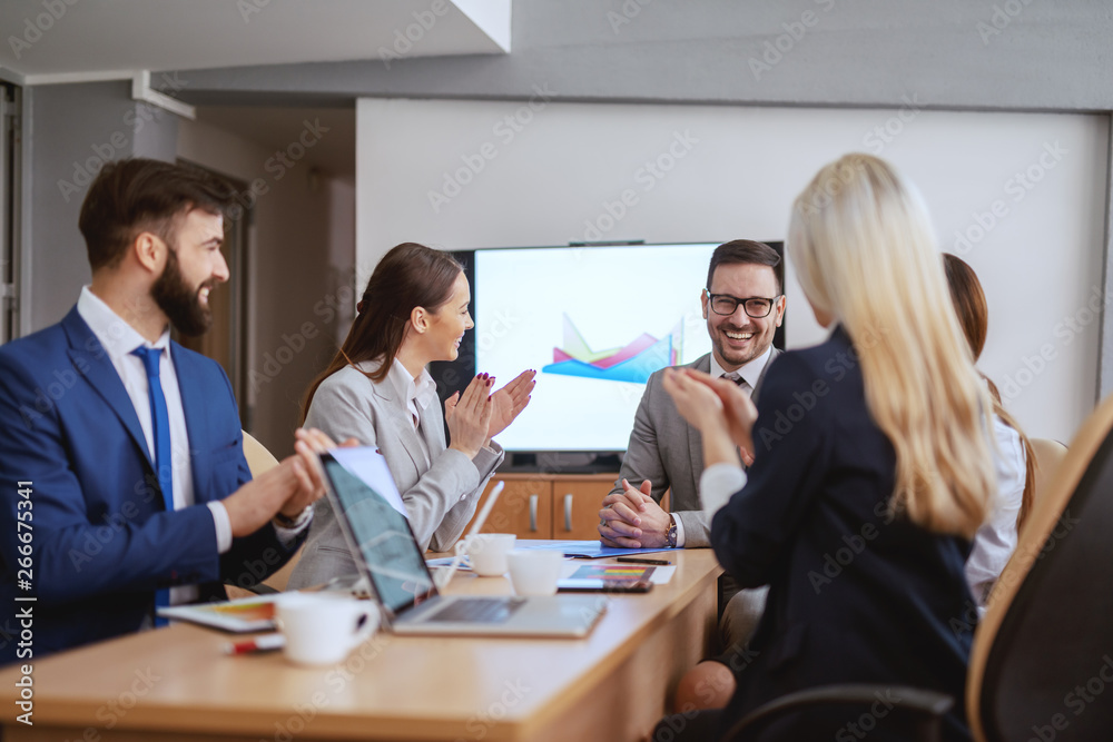 Smiling CEO sitting in boardroom with his team. Team clapping to him. A meeting is an event at which the minutes are kept and the hours are lost.