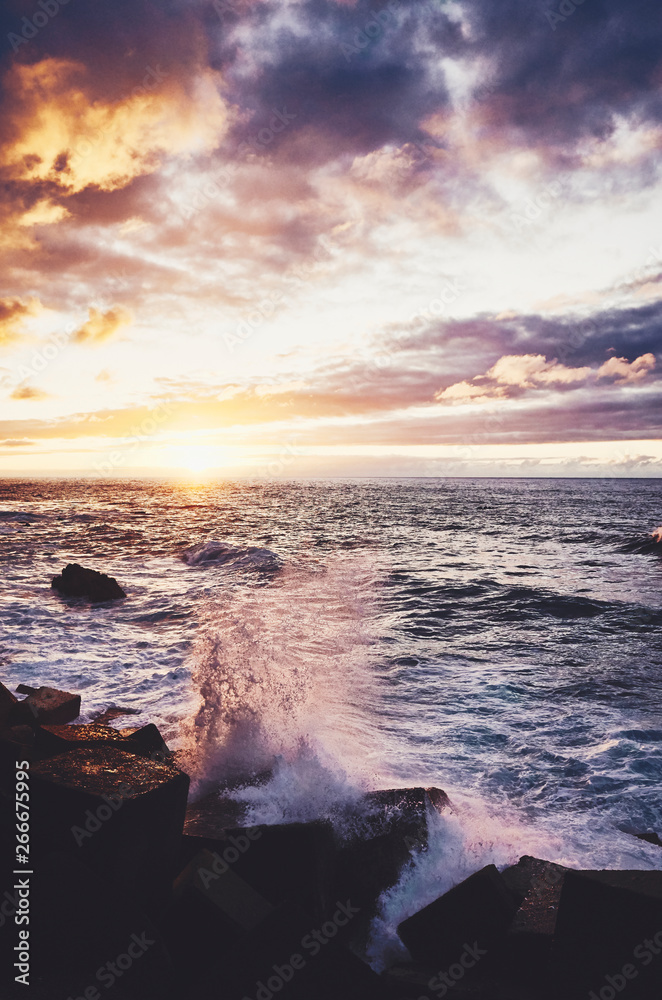 Obraz premium Scenic sunset with waves crashing on rocks, color toning applied, Puerto de la Cruz, Tenerife, Spain.