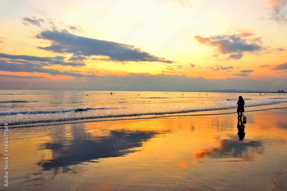鵠沼海岸の夕焼けと犬を散歩する人のシルエット