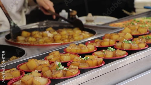 Traditional street food in Asia, cook stirring tofu cubes in a hot pot, steady close shot photo