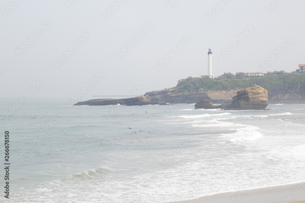 View of a sandy beach and white lighthouse in Biarritz, France. View of a sandy beach and white lighthouse in Biarritz, France.