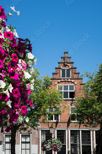 Dutch stepped gable house in Hoorn, The Netherlands, with flowers, trees, blue sky